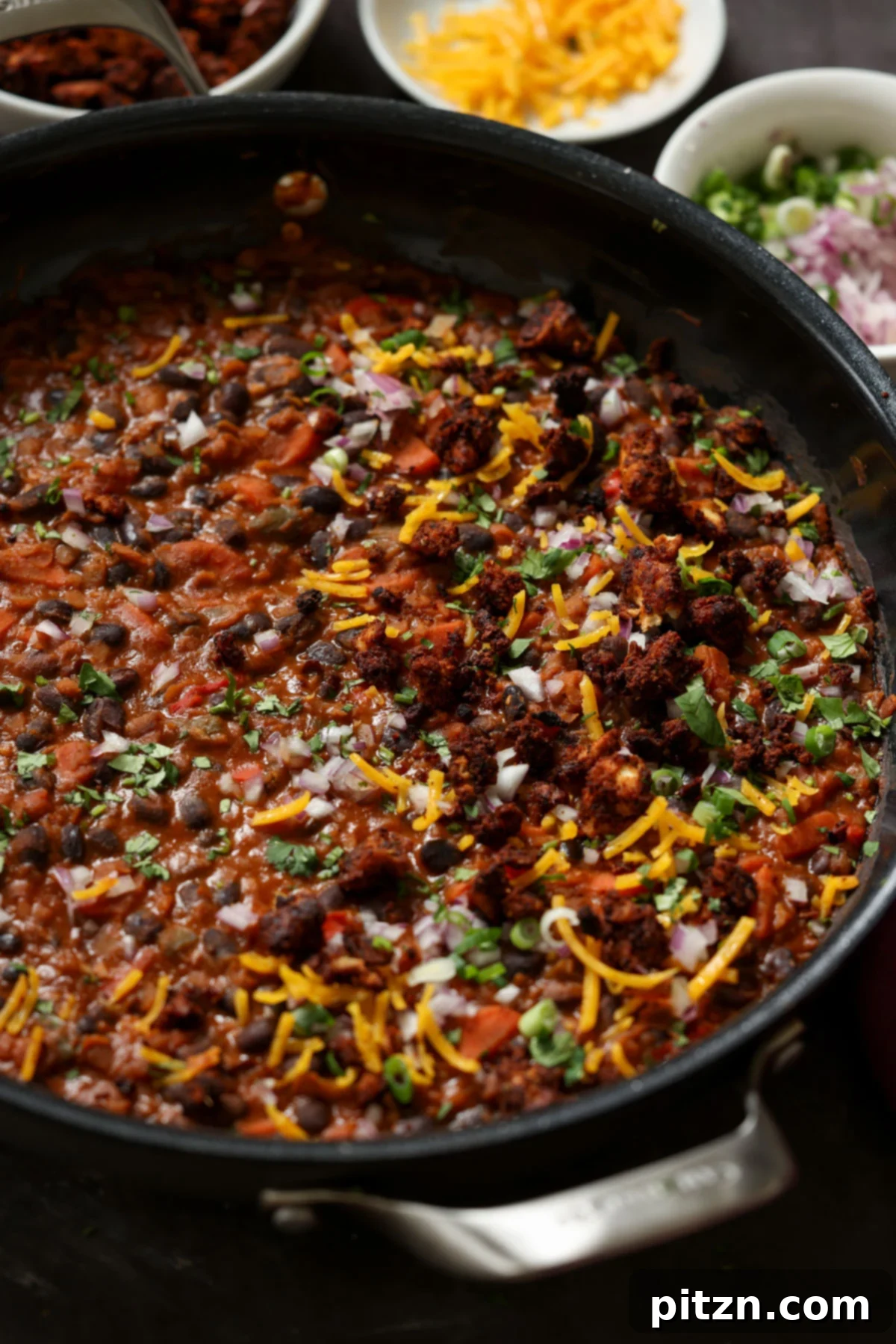 Close-up of the cooked black beans and lentils in a pan, now adorned with colorful toppings like fresh cilantro and diced onions, enhancing its visual appeal.