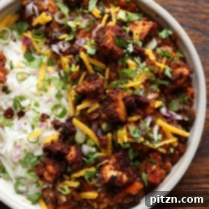 Vibrant Chorizo Tofu Burrito Bowl with rice, fresh pico de gallo, and a dollop of creamy vegan cheese on top, a perfect vegan meal.
