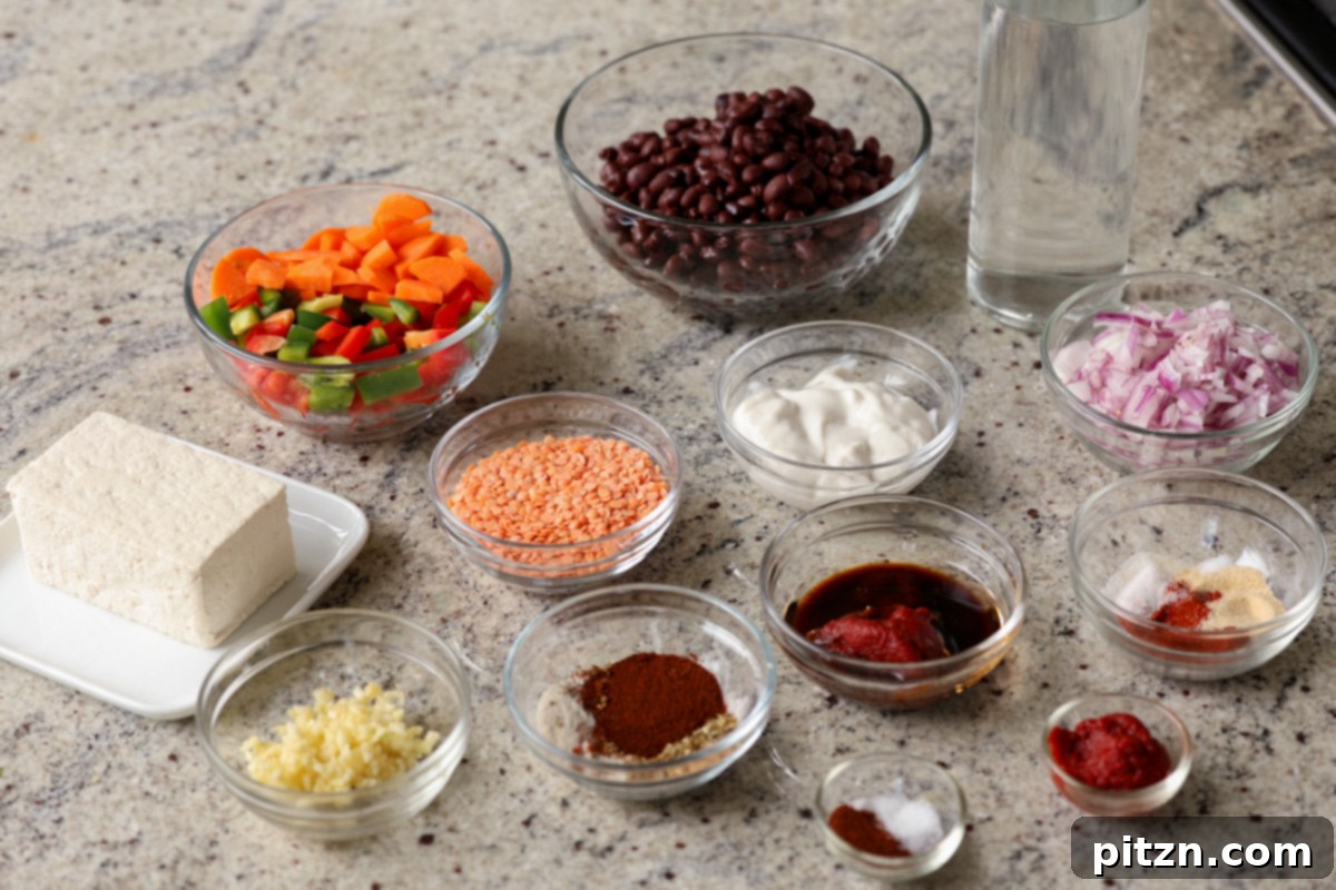 A collection of ingredients for the burrito bowl laid out on a kitchen counter, including fresh tofu, various spices, black beans, and colorful vegetables in bowls, ready for preparation.