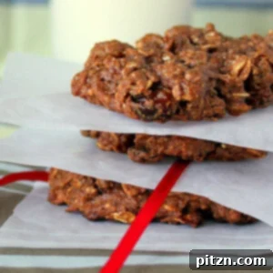 A stack of chocolate oatmeal raisin cookies separated by parchment paper