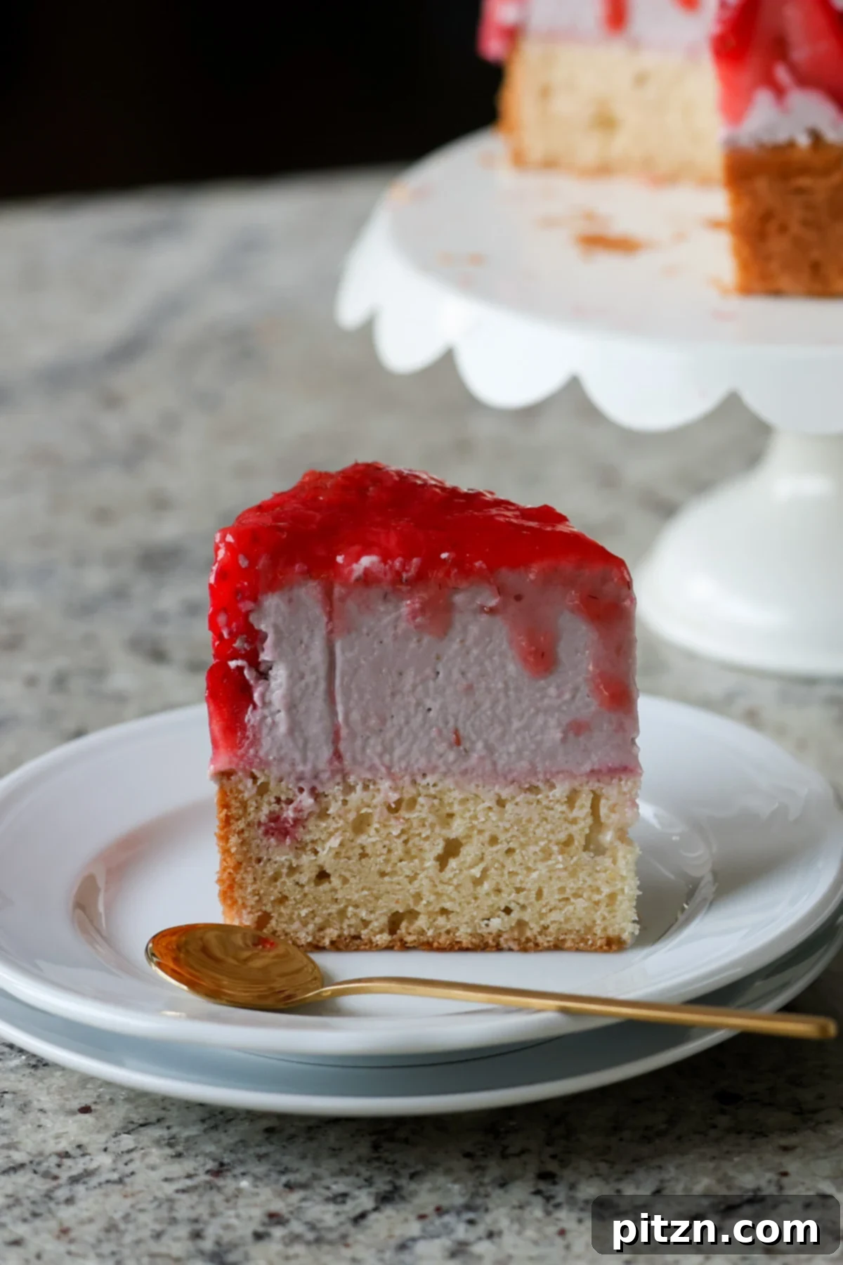 Vegan Strawberry Mousse Cake Gluten Free 4 A pristine slice of strawberry mousse cake on a white plate, accompanied by a spoon