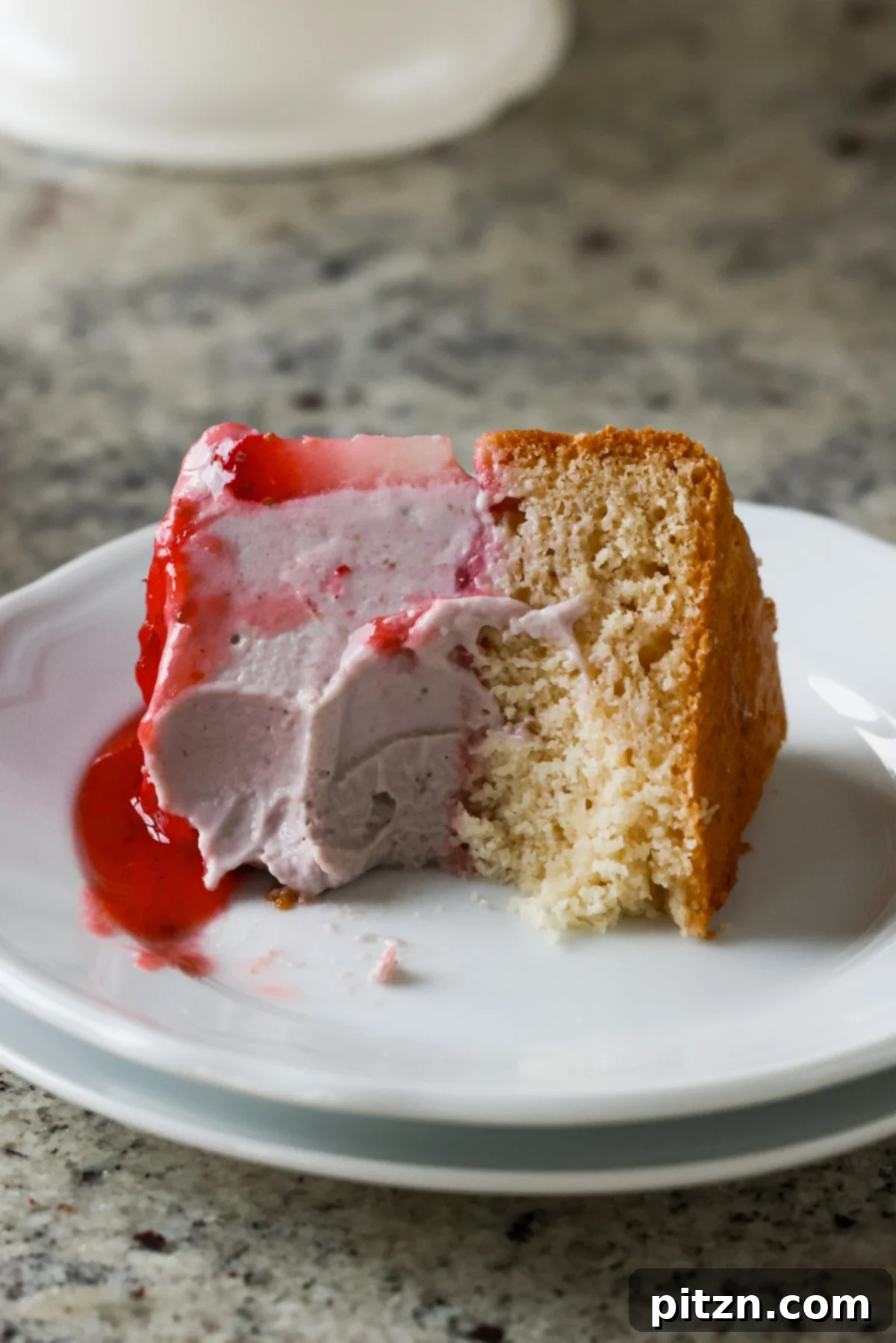 Vegan Strawberry Mousse Cake Gluten Free 5 A slice of strawberry mousse cake on a plate with a small bite taken out, showing the layers