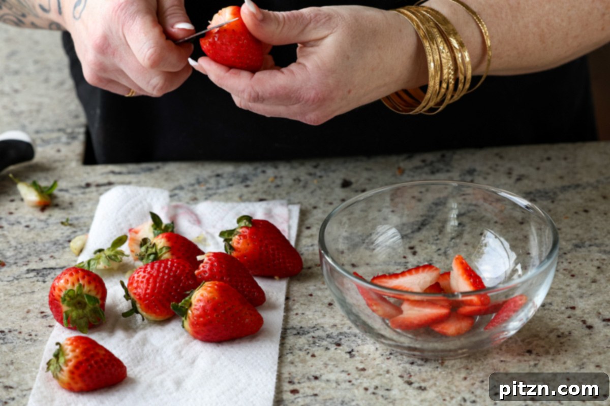 Vegan Strawberry Mousse Cake Gluten Free 9 Fresh strawberries being thinly sliced on a cutting board, preparing for cake decoration