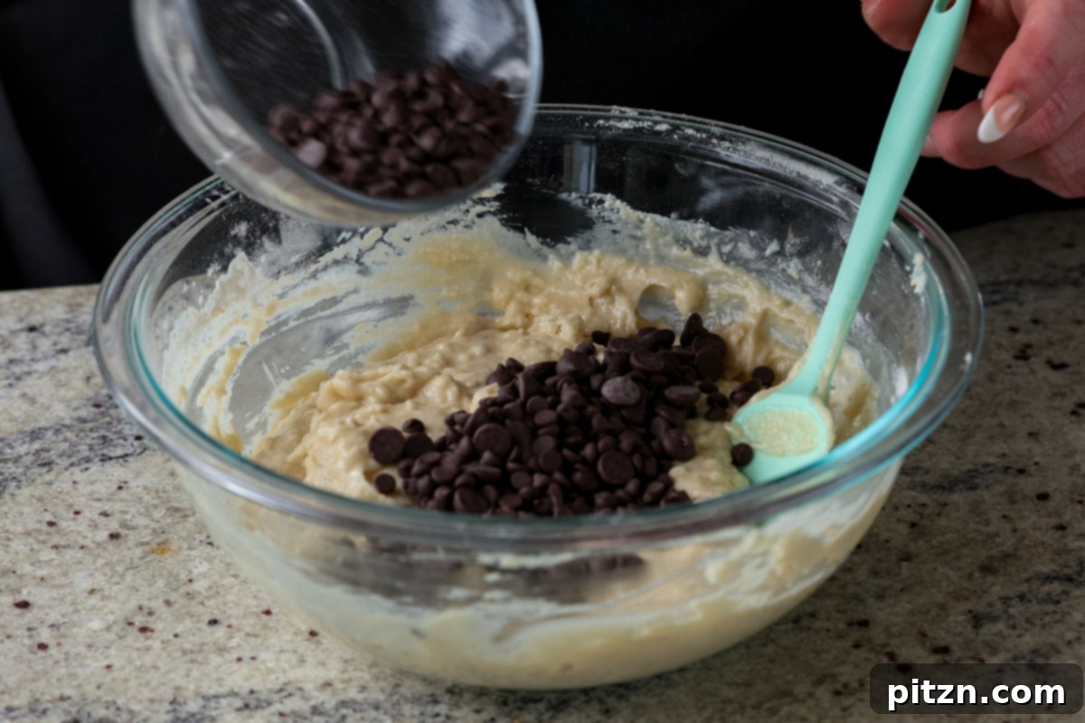 Unbelievably Fluffy Vegan Gluten-Free Chocolate Chip Muffins 11 Adding vegan chocolate chips into the prepared muffin batter in a bowl.