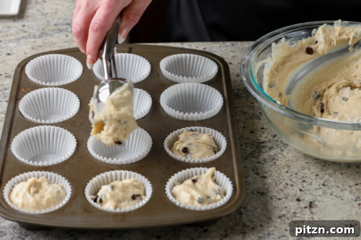 Unbelievably Fluffy Vegan Gluten-Free Chocolate Chip Muffins 13 Scooping muffin batter into paper-lined muffin tins using a cookie scoop.
