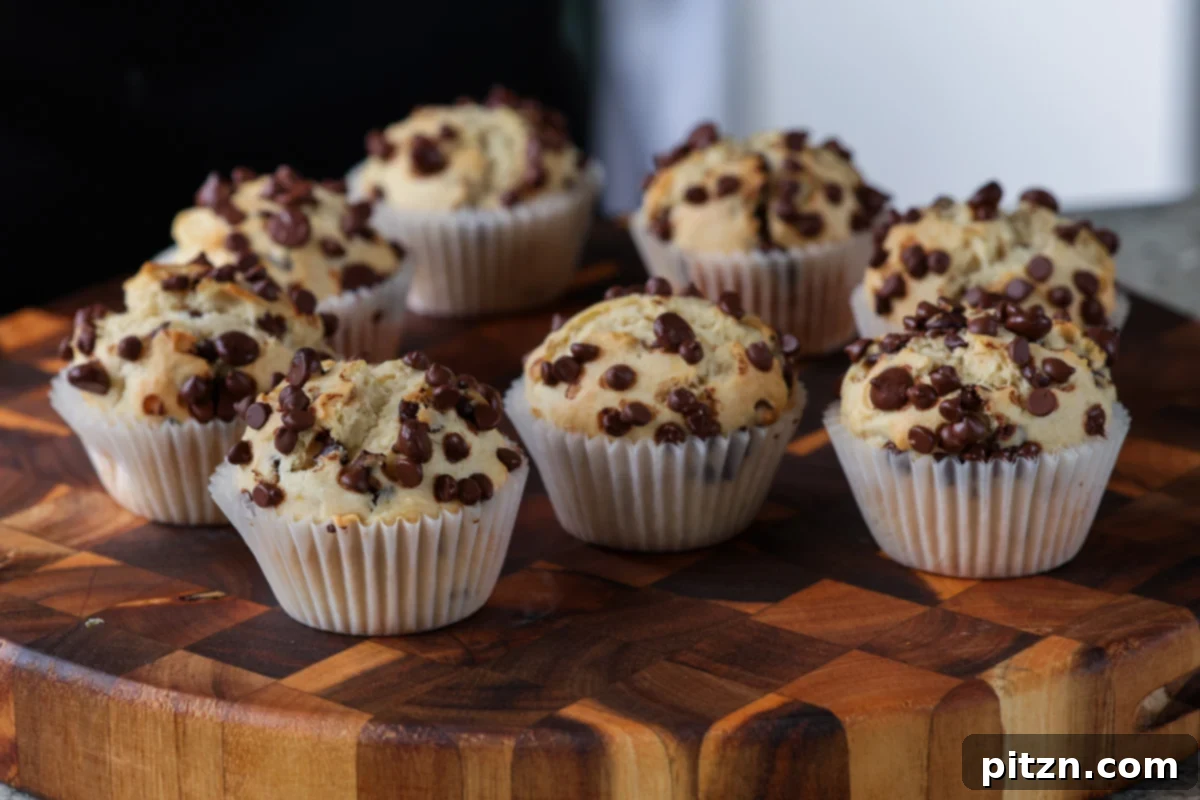 Unbelievably Fluffy Vegan Gluten-Free Chocolate Chip Muffins 15 A large batch of freshly baked vegan chocolate chip muffins artfully arranged on a wooden cutting board, ready to be enjoyed.