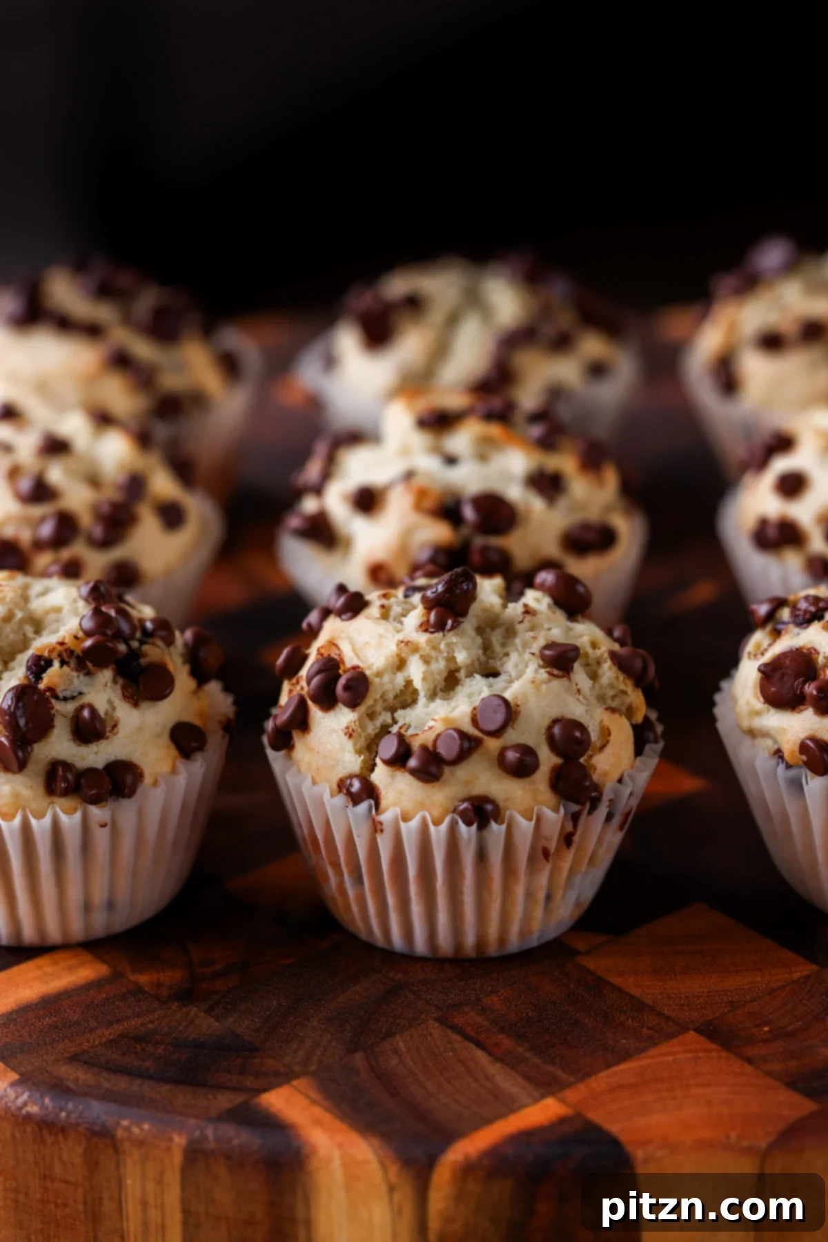 Unbelievably Fluffy Vegan Gluten-Free Chocolate Chip Muffins 3 A cluster of warm vegan chocolate chip muffins cooling on a wooden cutting board, highlighting their generous chocolate chip topping.