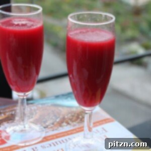 Two glasses of vibrant Mango Beet Spiced Cooler garnished with fresh mint.