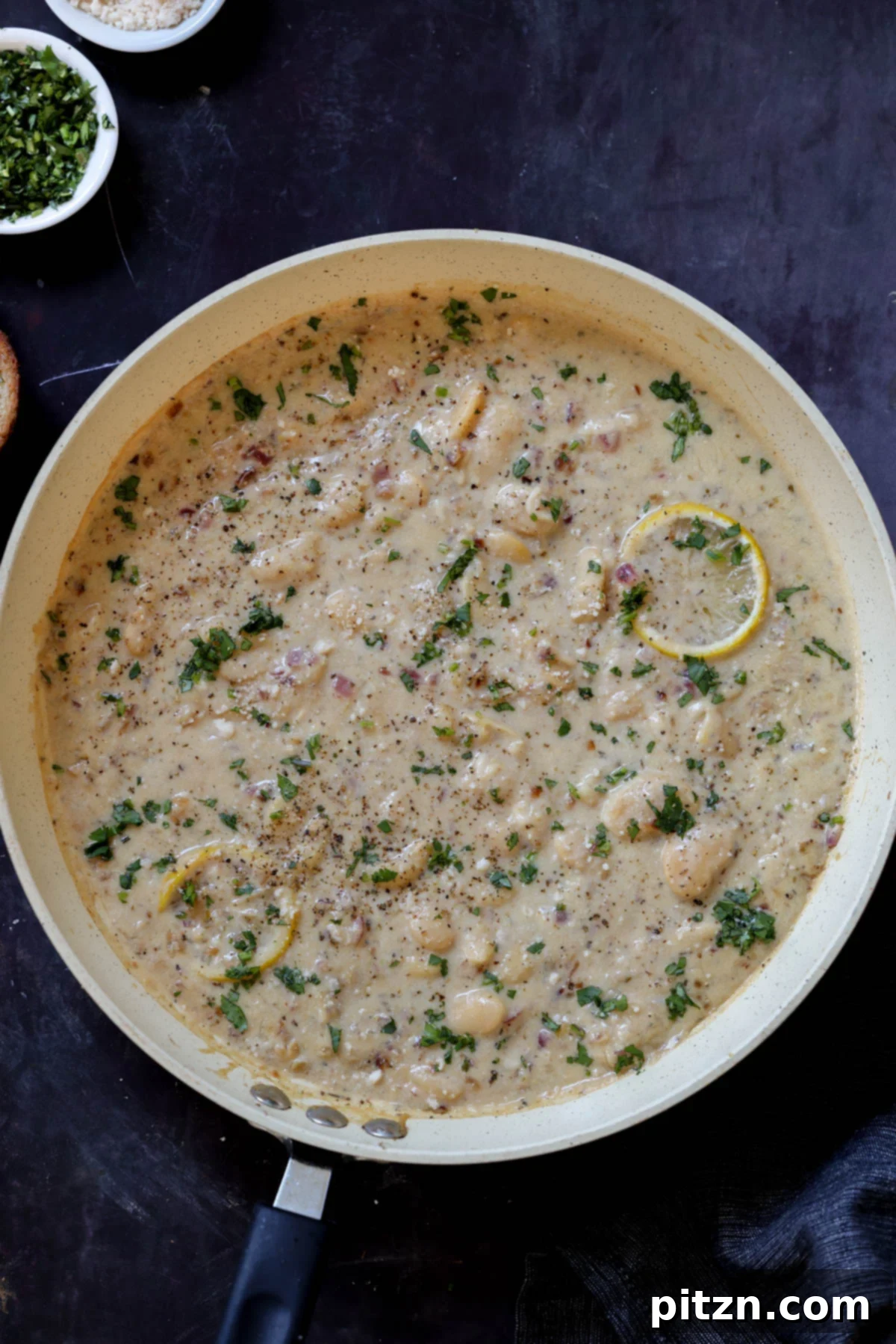 A vibrant pan of lemon garlic butter beans, garnished with fresh parsley and lemon slices, ready to be served