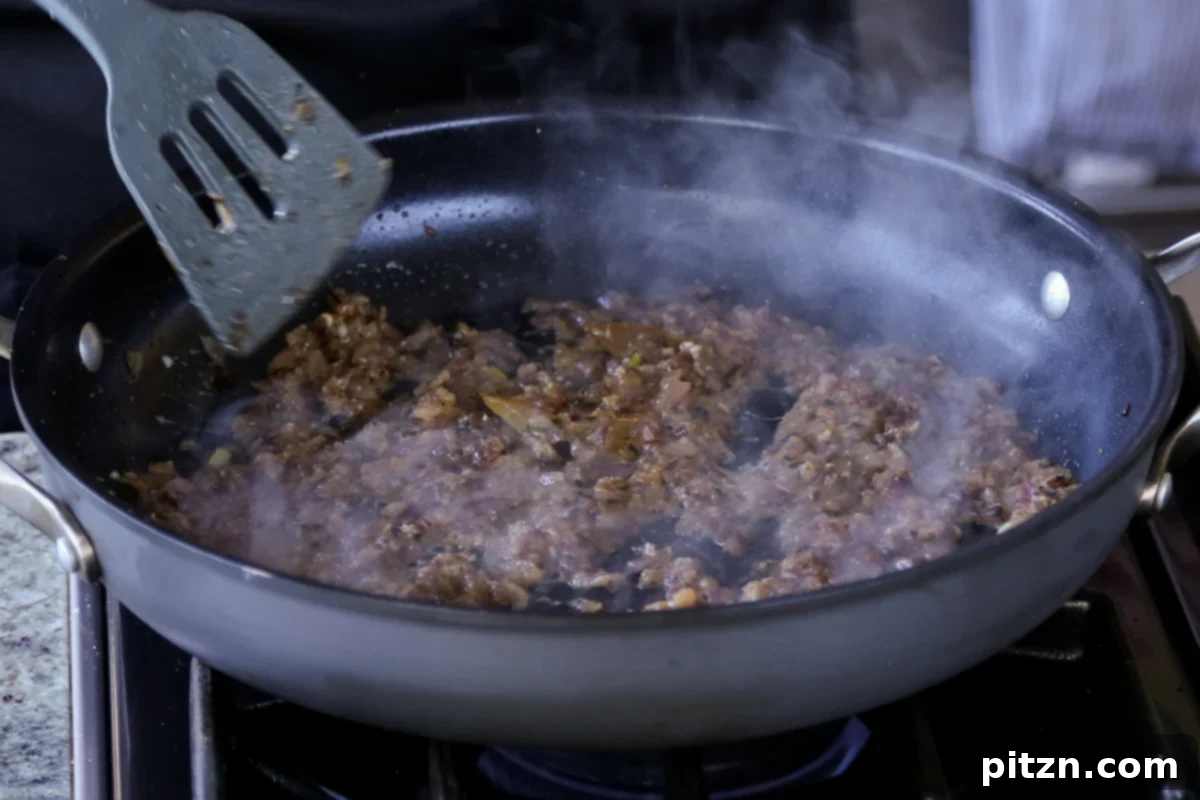 The ginger garlic paste fully mixed into the onion and spice mixture, creating a cohesive, fragrant curry base.