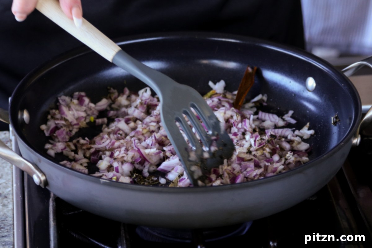 Finely chopped onions and ground spices being mixed together in a hot skillet, creating the flavorful base.