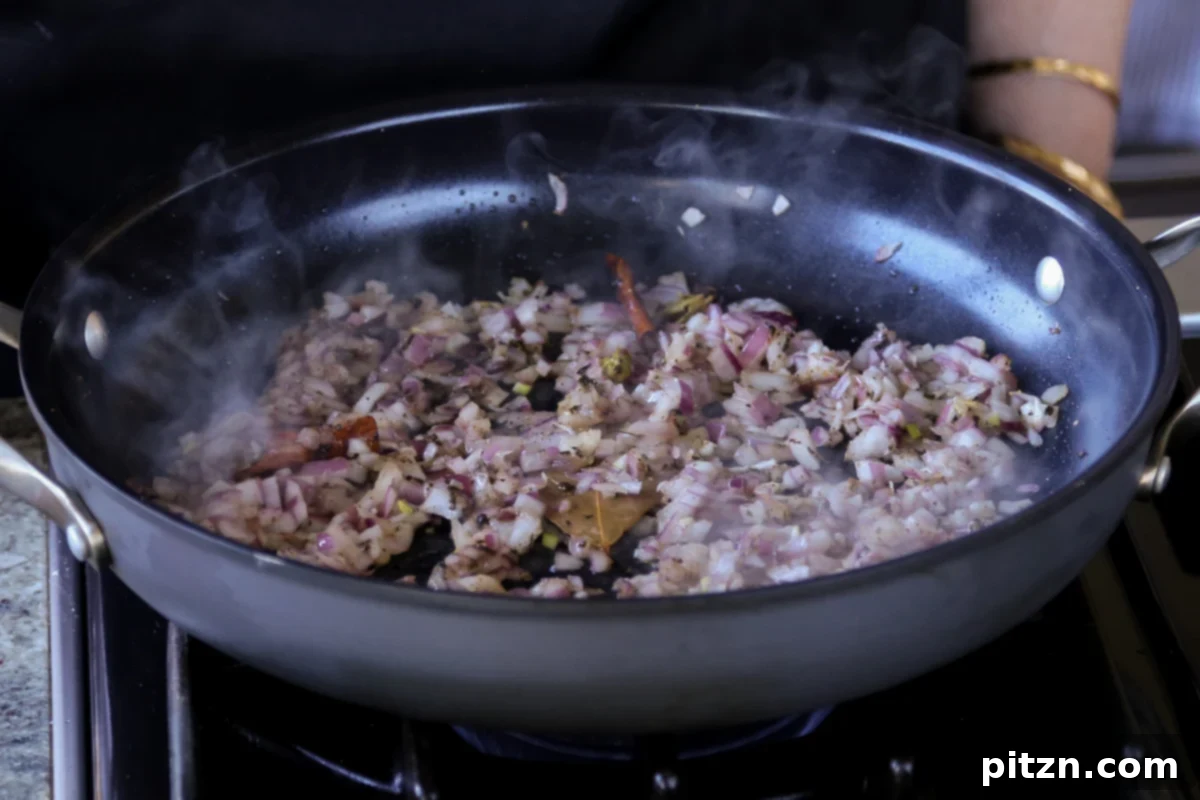 A close-up view of golden-brown cooked onions and fragrant spices in the pan, showing their caramelized texture.