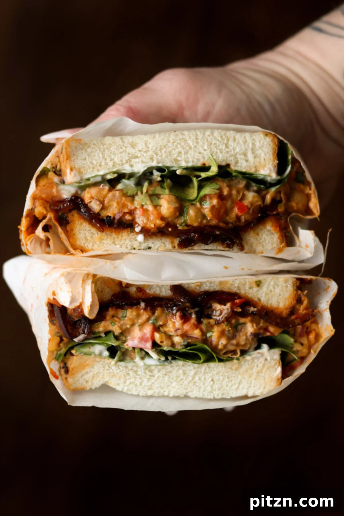 Gochujang Chickpea Sandwich with Sweet and Spicy Caramelized Onions 2 hand holding a gochujang chickpea salad sandwich