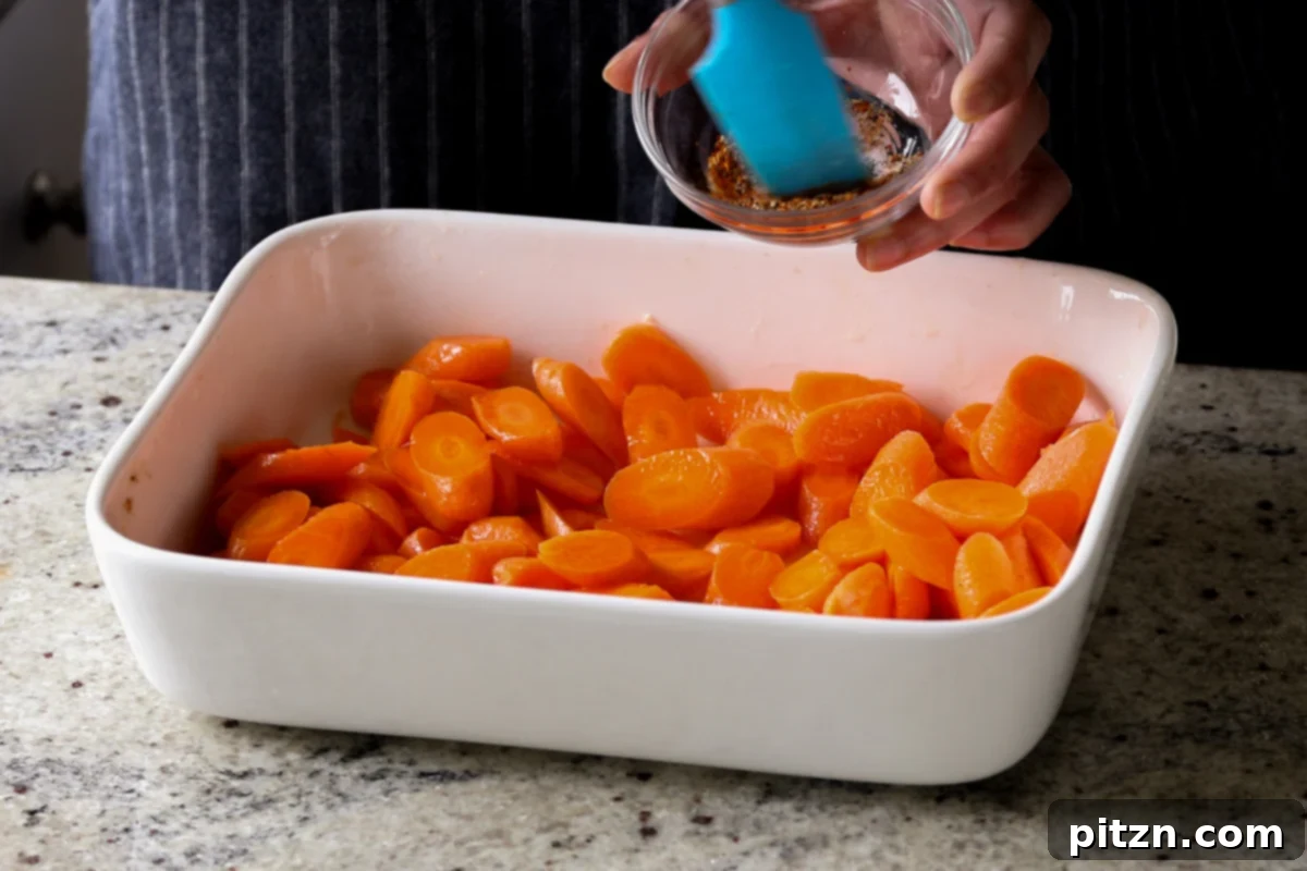 Sprinkling spices over the carrots in the baking pan before roasting.
