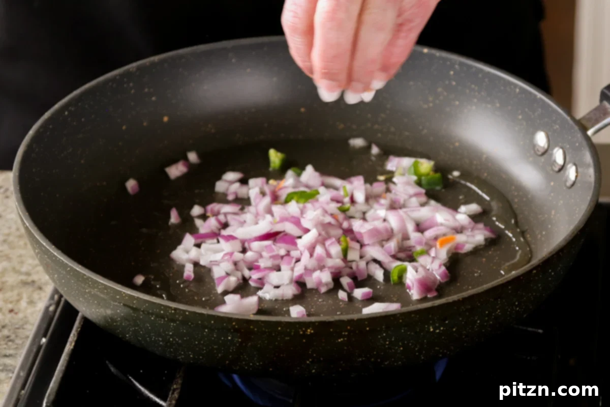 Chopped onions sautéing in a pan, beginning to turn golden.