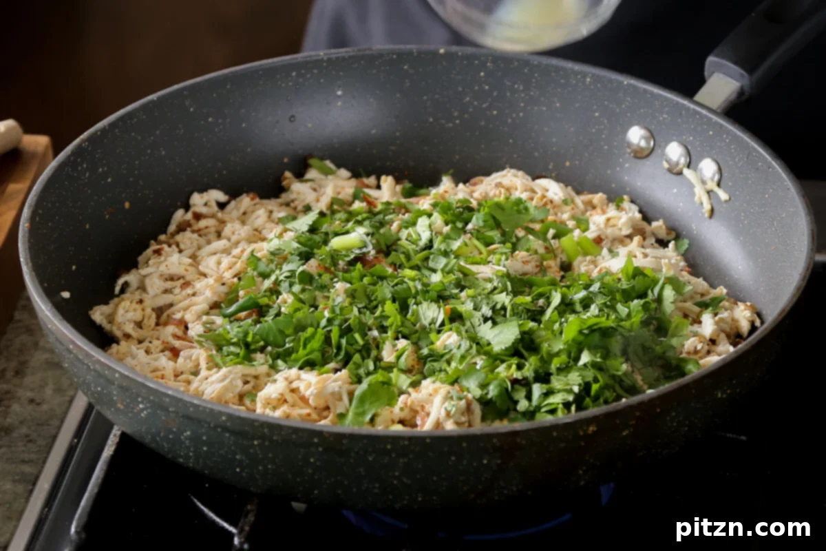 Adding more chopped cilantro to the tofu mixture in the pan.