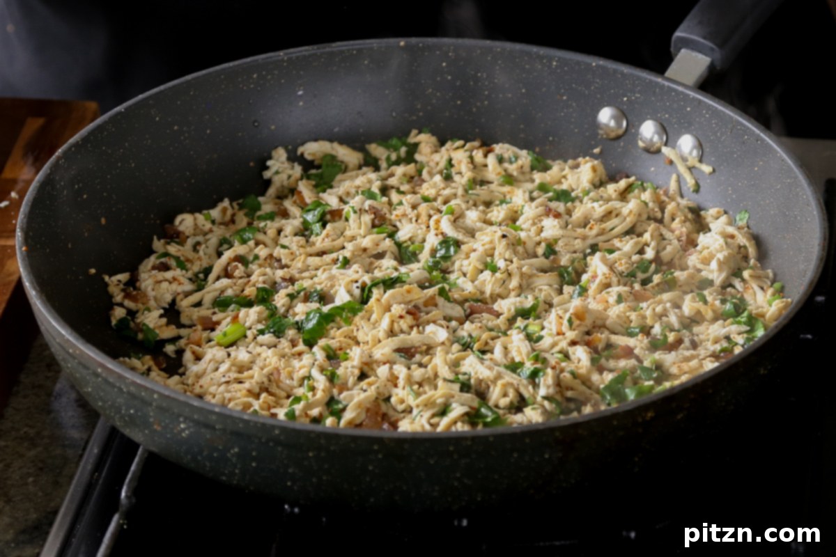 Cilantro lime shredded tofu in a pan, vibrant and perfectly cooked after cilantro has been tossed in.