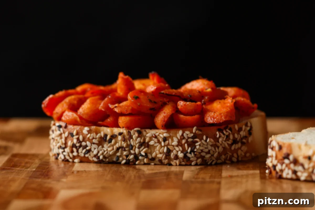 Bread topped with warm roasted carrots, ready for the shredded tofu to complete the sandwich.
