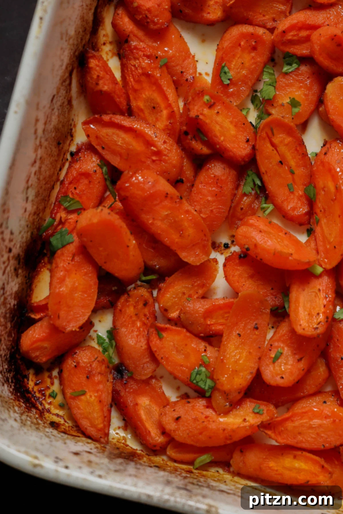 Close-up of perfectly roasted carrots in a baking pan, showing their caramelized edges.
