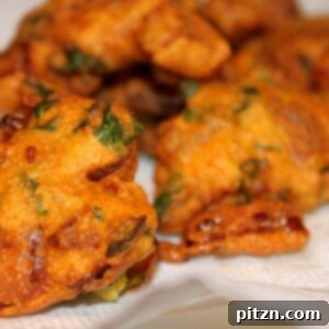 Crispy Onion Fritters: Pure Comfort 2 Onion fritters lying on some white parchment paper, ready to be served