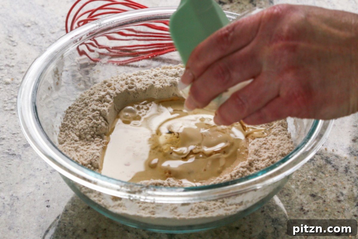 Luscious Triple Ginger Vegan Gingerbread Cake 12 Molasses and oil being added to the center well of dry ingredients, already containing non-dairy milk, to form the wet component of the vegan gingerbread cake batter.