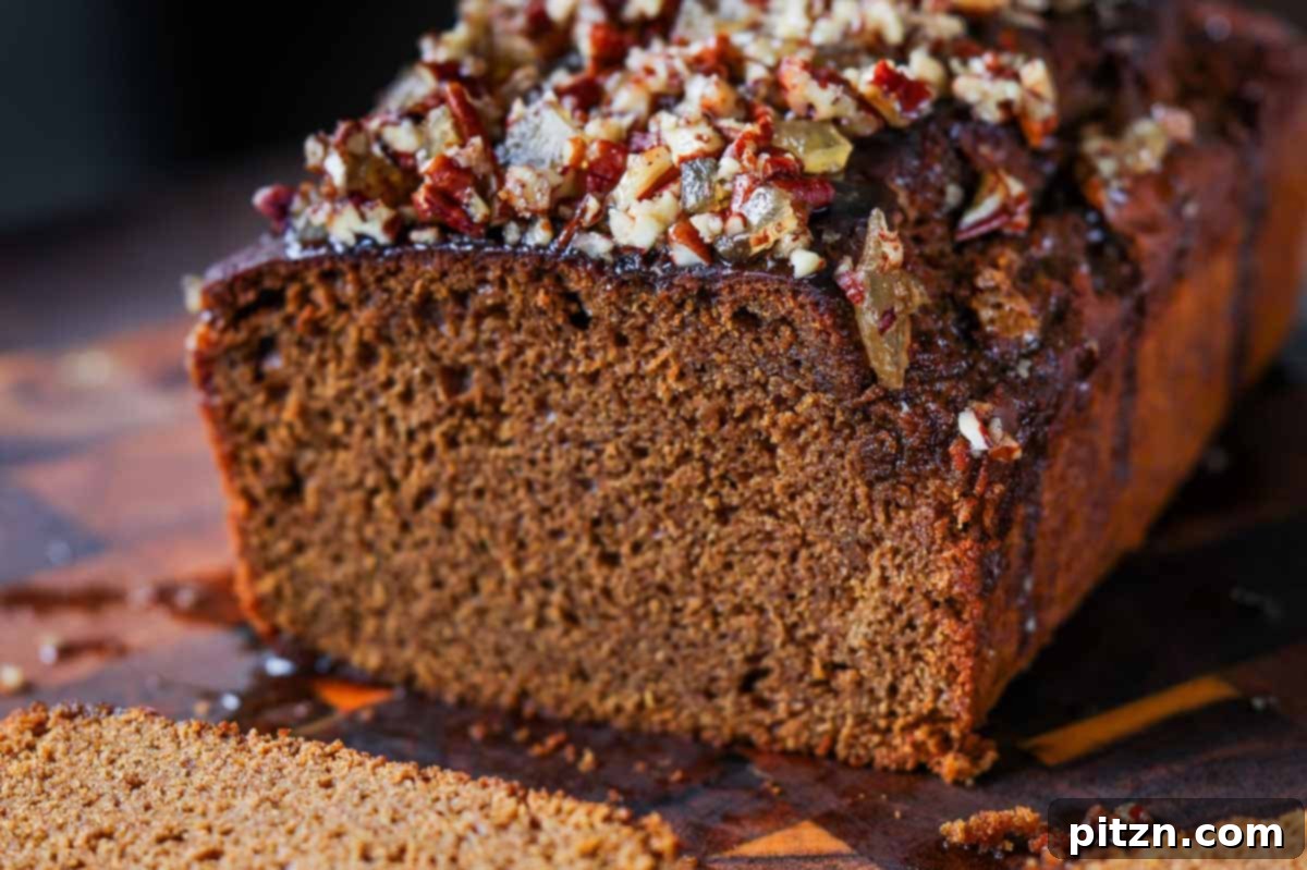Luscious Triple Ginger Vegan Gingerbread Cake 21 A perfectly baked and glazed vegan gingerbread cake on a wooden cutting board, with a large slice removed, ready to be served and enjoyed.