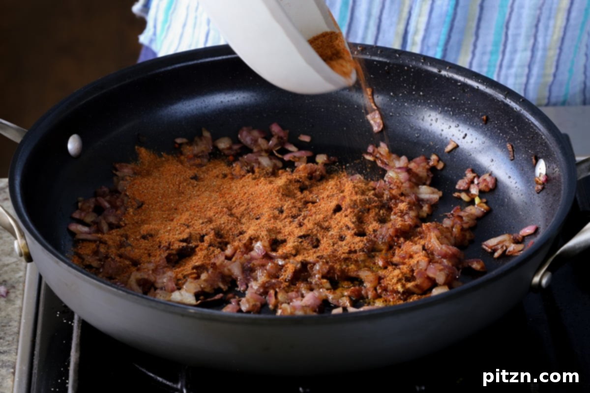 Robust Vindaloo Potato and Lentil Curry 14 adding vindaloo spice mix to the cooked onions