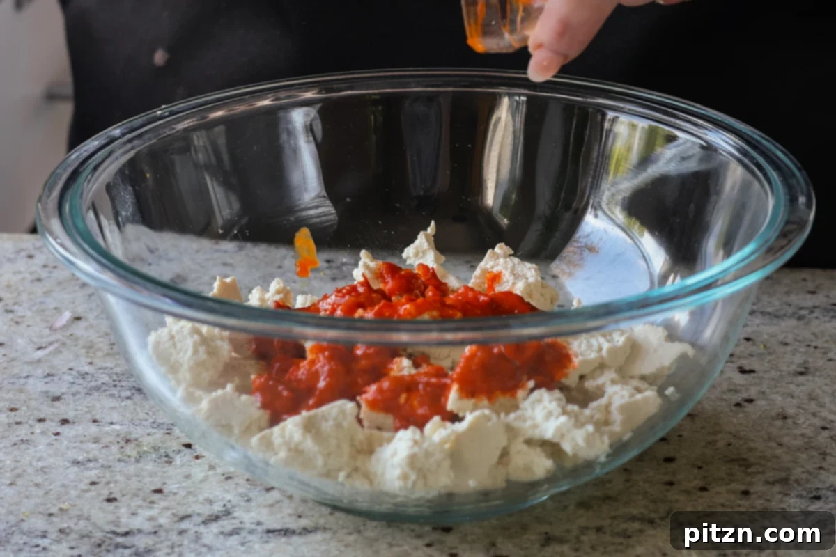 30-Minute Harissa Tofu Bowls for All Diets 8 adding harissa to the tofu in the bowl