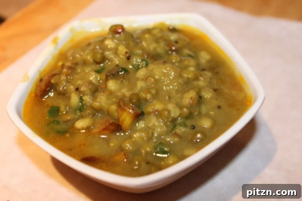 Ingredients for Green Mung Daal laid out on a wooden counter, including spices, onions, and mung beans