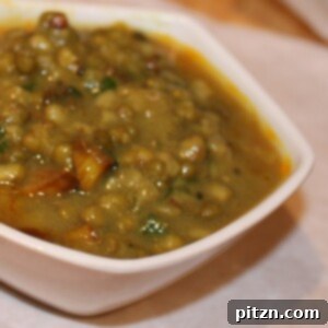 Green mung daal served in a white bowl, garnished with fresh cilantro