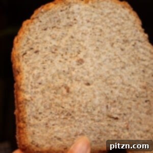 A slice of an orange blueberry multigrain loaf being held up towards the camera