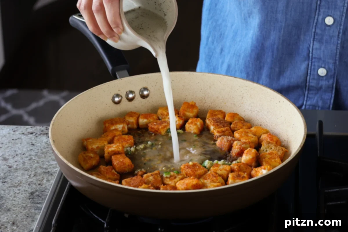Flaky Indo Chinese Chilli Garlic Tofu Parcels 17 Pouring a cornstarch slurry into the sauce to thicken it, creating a rich, glossy consistency.