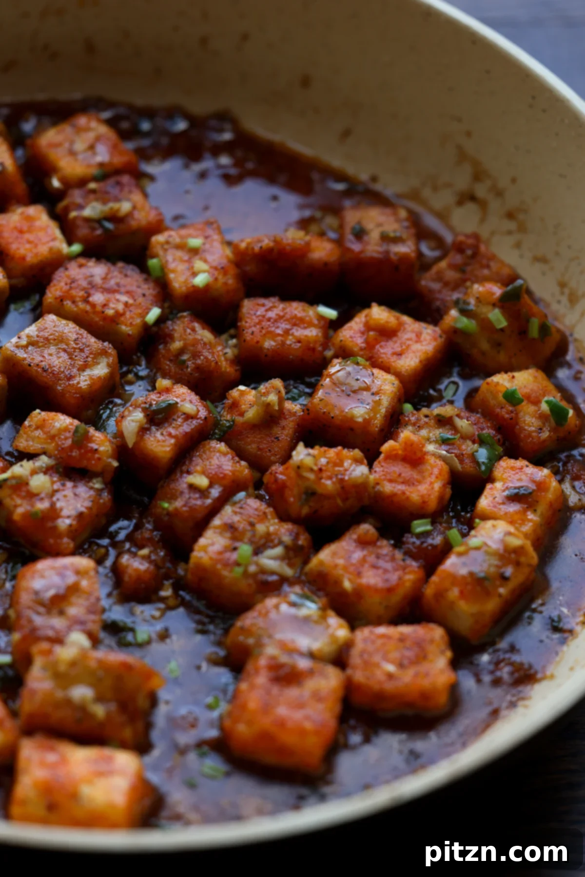 Flaky Indo Chinese Chilli Garlic Tofu Parcels 3 Chilli garlic tofu stir-fry cooking in a pan, showcasing the rich red sauce and crispy tofu cubes.