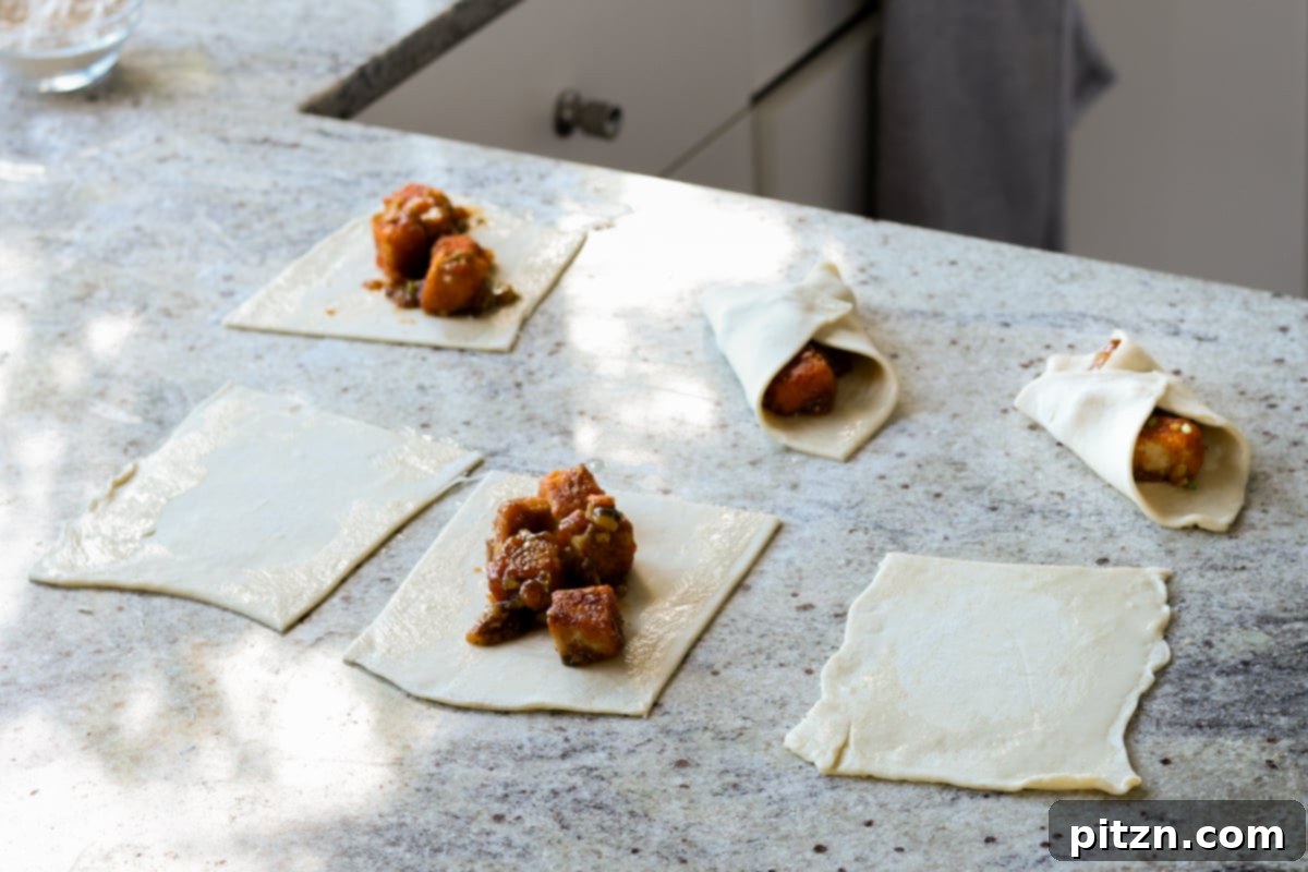 Flaky Indo Chinese Chilli Garlic Tofu Parcels 24 The process of folding two diagonal corners of the puff pastry over the tofu filling to create a sealed parcel.