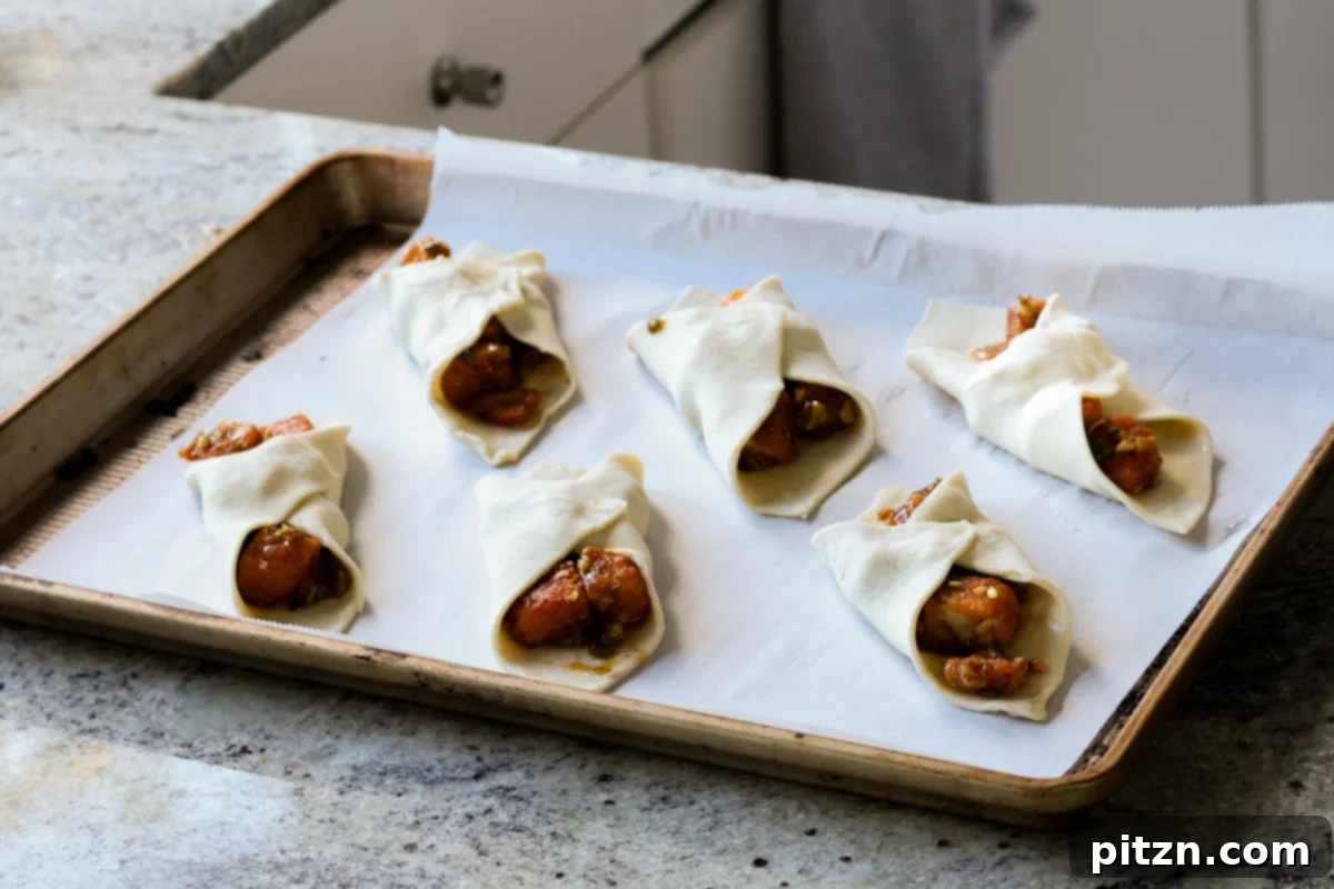 Flaky Indo Chinese Chilli Garlic Tofu Parcels 25 Several filled and folded tofu puff pastry parcels arranged on a parchment-lined baking sheet, brushed and ready for the oven.