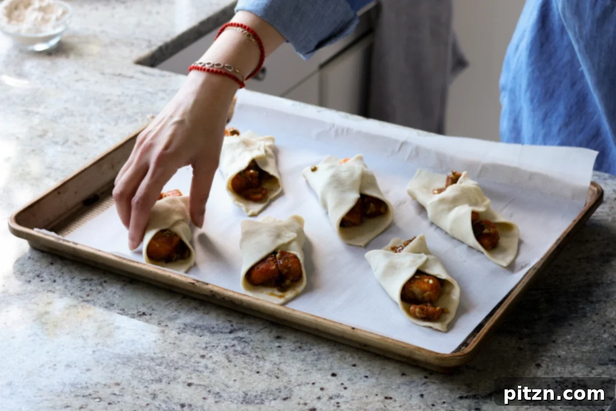 Flaky Indo Chinese Chilli Garlic Tofu Parcels 26 Hand carefully placing a filled tofu puff pastry parcel onto a baking sheet, ensuring proper spacing.