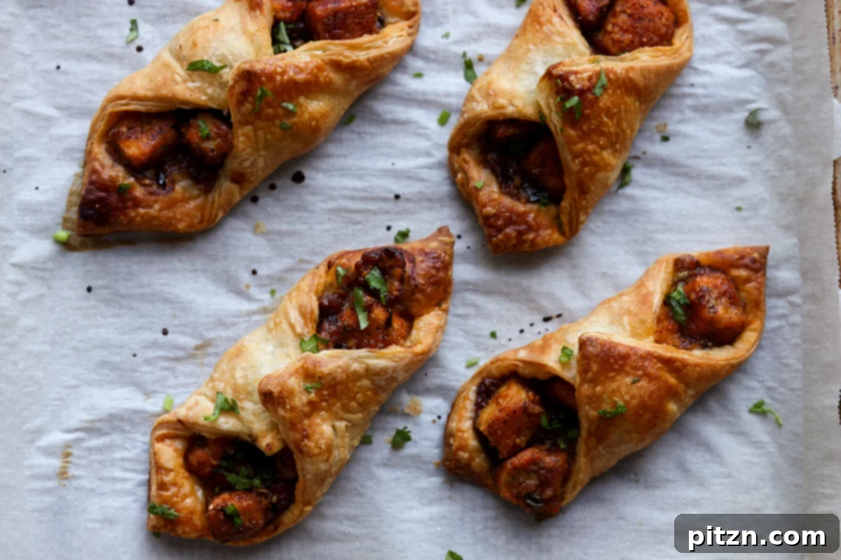 Flaky Indo Chinese Chilli Garlic Tofu Parcels 27 Freshly baked and garnished chilli garlic tofu puffs on a baking sheet, showcasing their golden, flaky exterior.