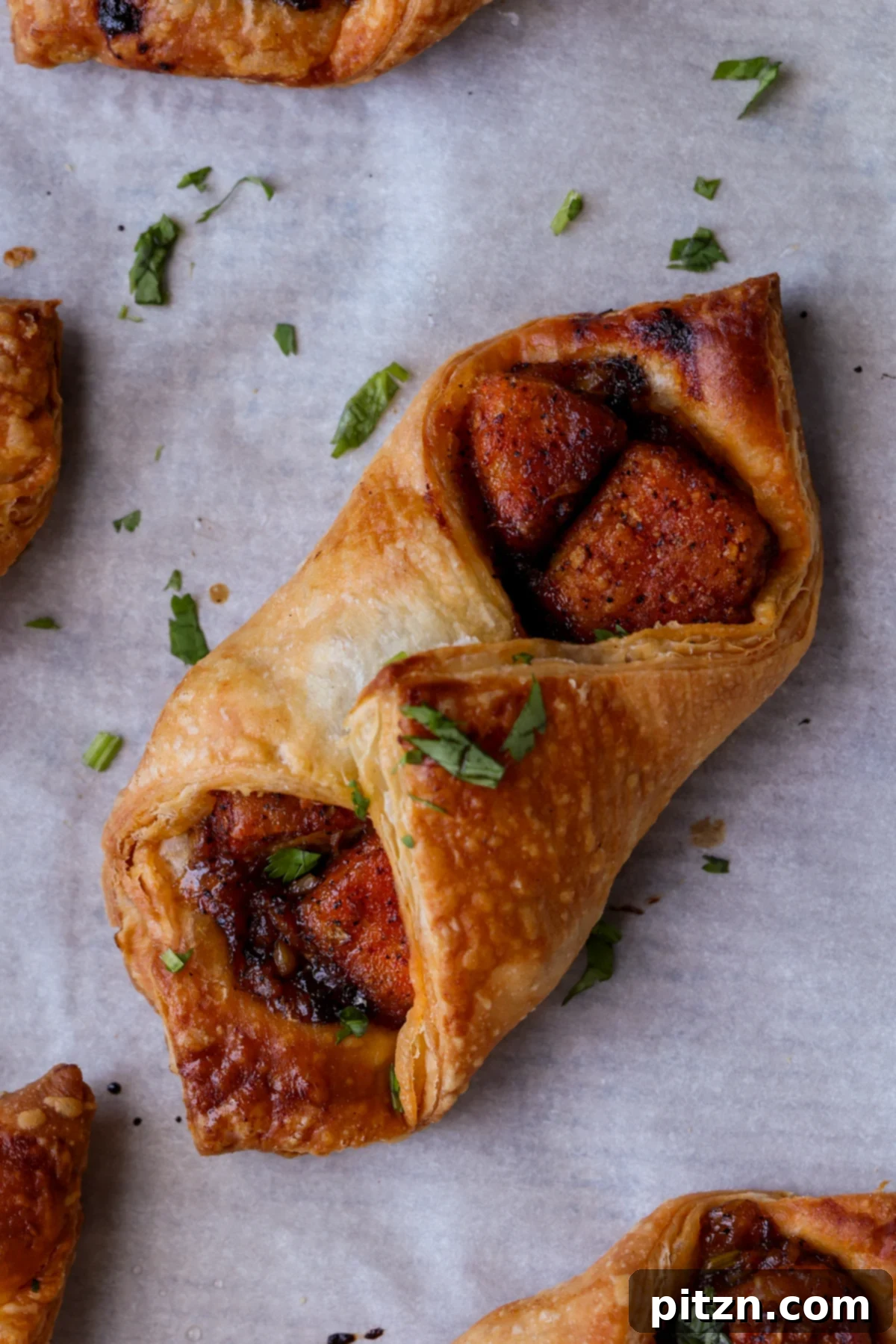 Flaky Indo Chinese Chilli Garlic Tofu Parcels 5 An array of unbaked chilli garlic tofu puff pastry parcels, neatly arranged on a baking sheet, brushed with a vegan egg wash alternative.