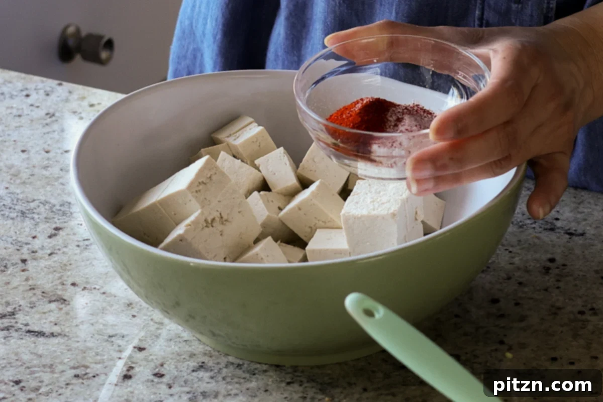 Flaky Indo Chinese Chilli Garlic Tofu Parcels 9 Tofu cubes being seasoned with Kashmiri chili powder and salt in a bowl.