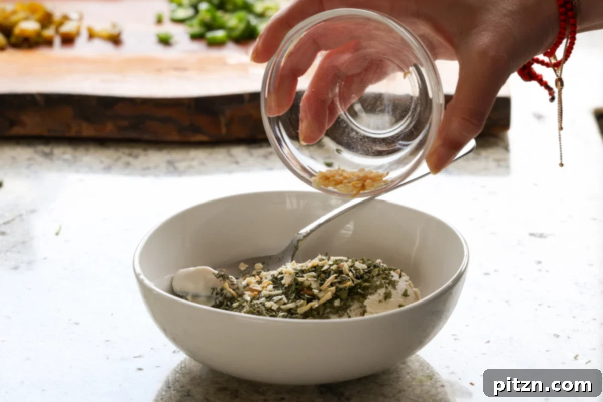 Vegan Jalapeño Popper Pinwheels 10 A spoonful of dried onion flakes being added to the mixing bowl with creamy vegan ingredients for the pinwheel filling.