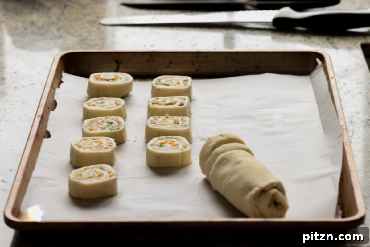 Vegan Jalapeño Popper Pinwheels 22 A chilled jalapeño popper pinwheel log being expertly sliced into even rounds on a cutting board.