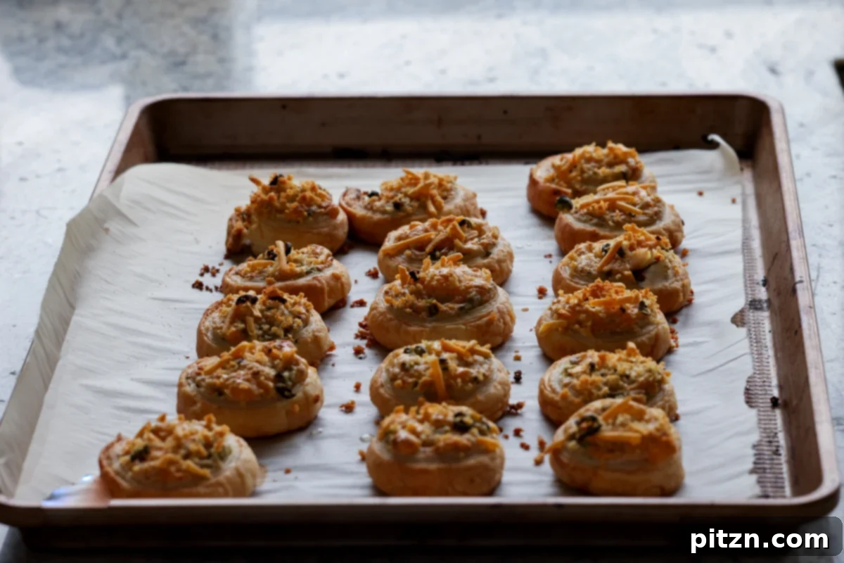 Vegan Jalapeño Popper Pinwheels 29 A baking sheet filled with freshly baked, golden-brown jalapeño popper pinwheels, perfectly puffed and crispy, just out of the oven.