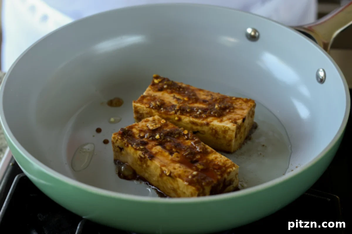 marinated teriyaki tofu cooking in a hot skillet, beginning to caramelize