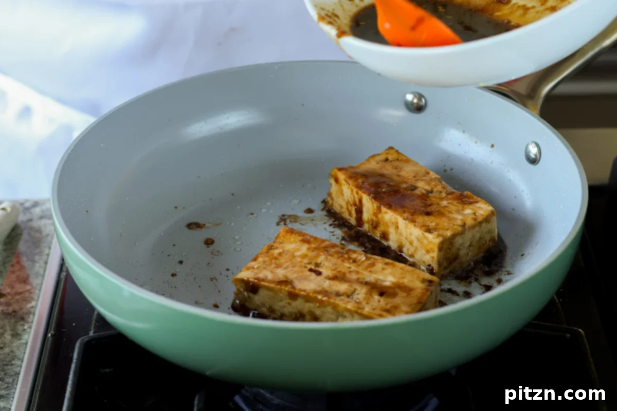 teriyaki tofu slabs flipped in the pan, showing the browned side and residual sauce