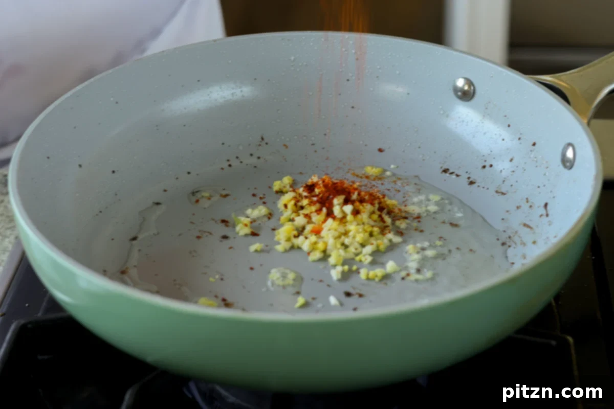 ginger, garlic, and gochugaru pepper flakes sizzling in oil in the pan to create the chili crisp