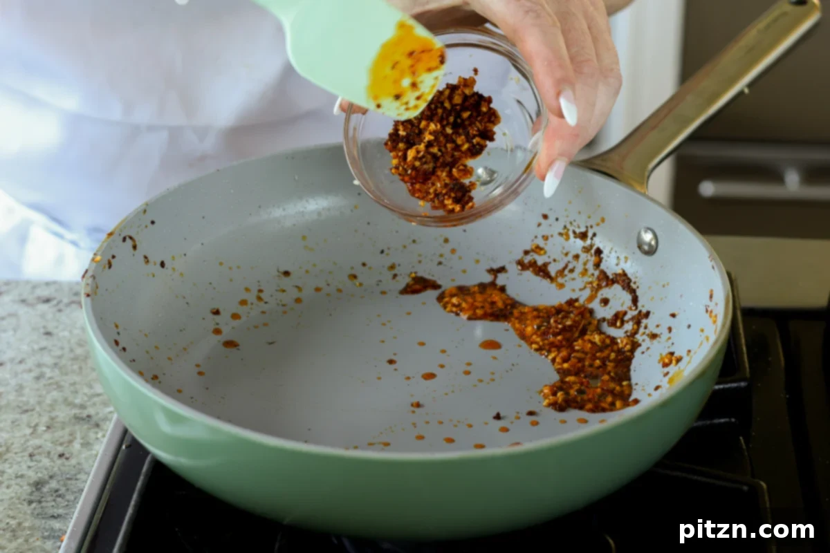 half of the freshly made chili crisp being scooped from the pan into a separate small bowl for garnish