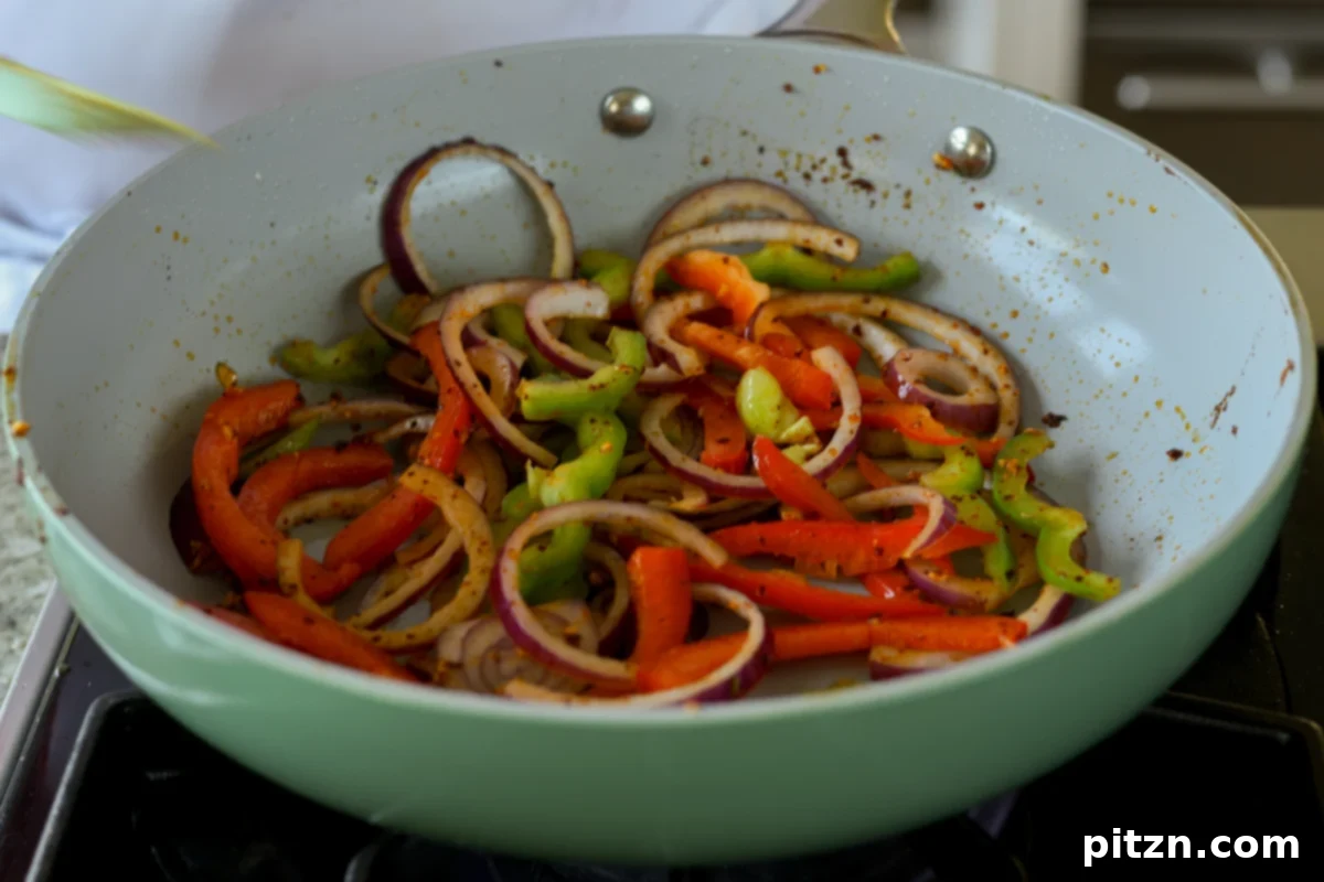 sliced onions and peppers added to the pan with the remaining chili crisp, beginning to sauté
