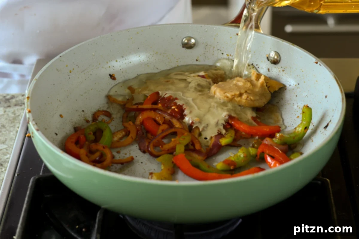 miso, sambal oelek, and tahini being added to the pan with vegetables and a cup of stock, ready to be mixed
