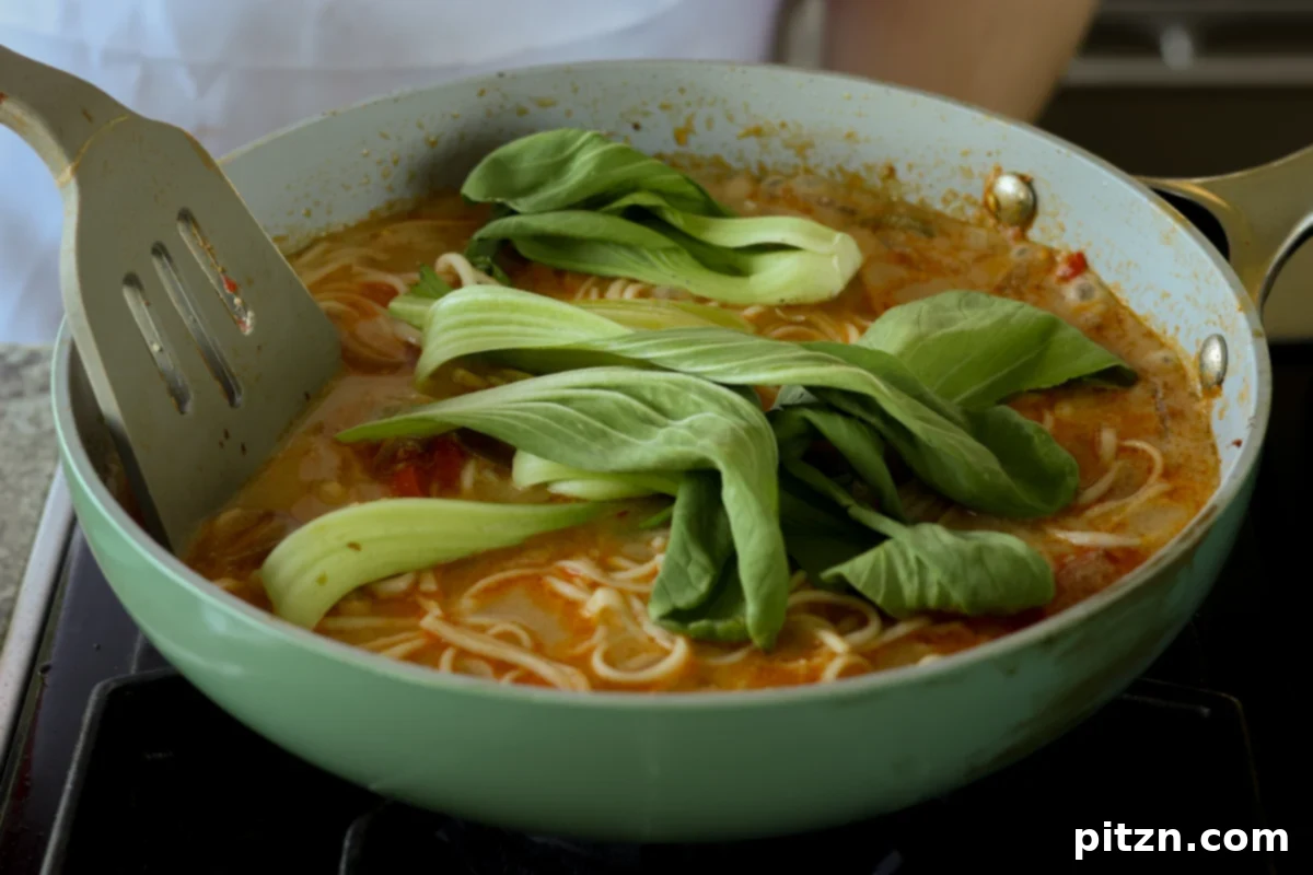 fresh baby bok choy added to the pan of cooked ramen noodles in tahini broth, gently pressed into the liquid