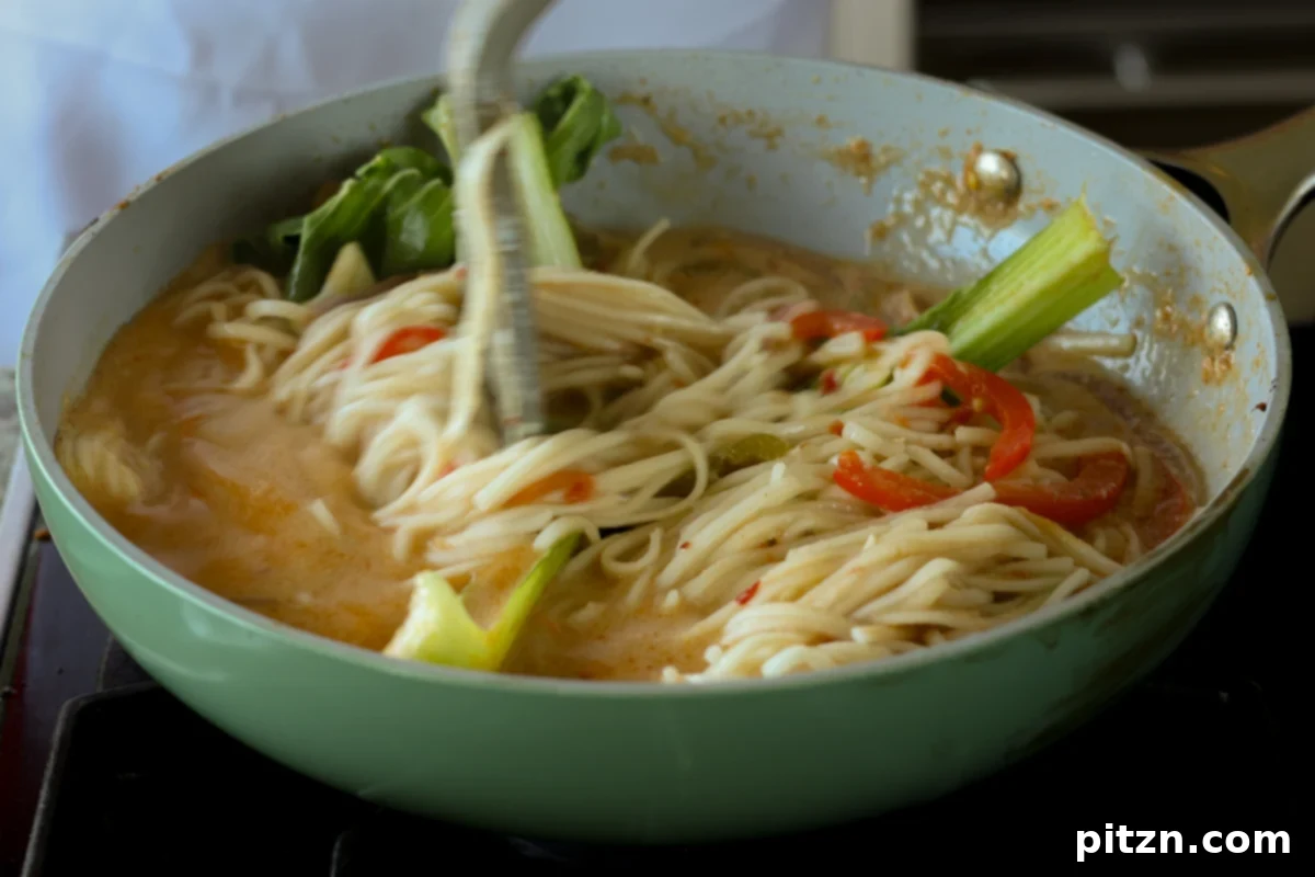 the creamy tahini ramen being gently mixed in the pan with chopsticks, ensuring even distribution of ingredients